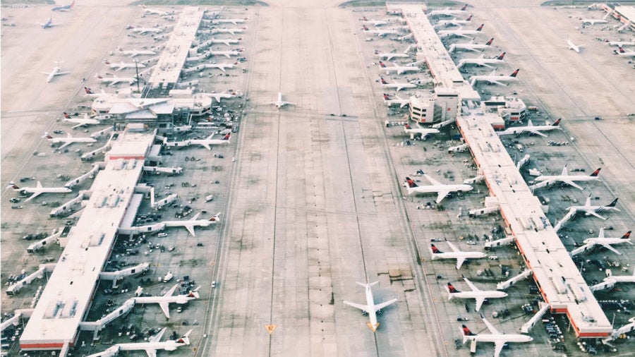 bird's eye view shot of many aeroplanes parked in rows on airfield