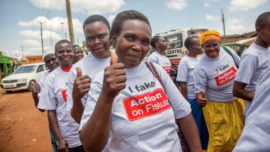 people wearing Action on Fistula t-shirts giving thumbs up