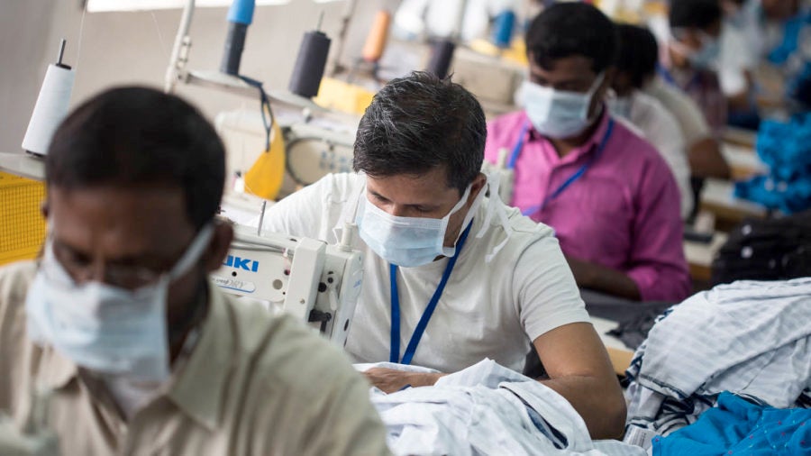 people sewing in factory, wearing face masks