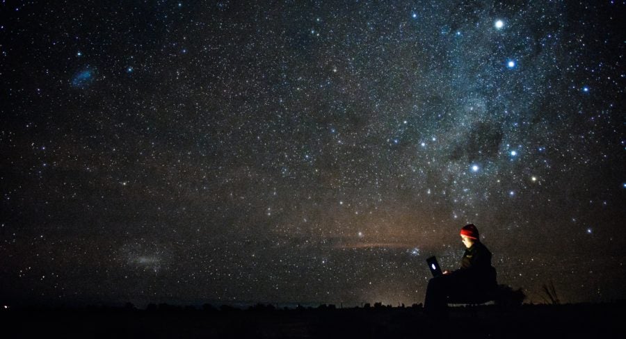 man with laptop under stars. Contemplating digital transformation