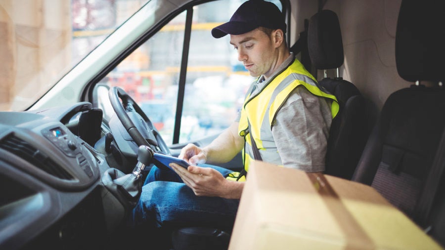 man from parcel delivery companies looking at tablet in truck