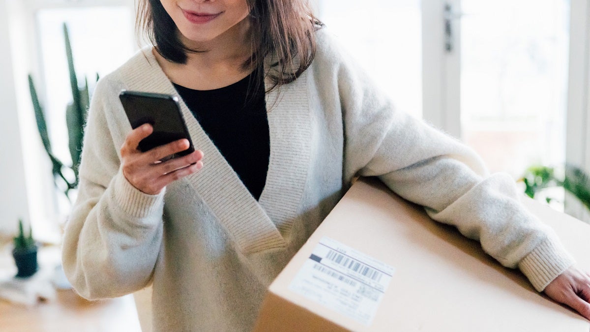 Woman looking at phone holding box