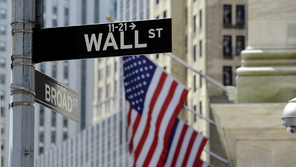 Wall,Street,Sign,With,Focus,On,Sign,,Blurred,American,Flag