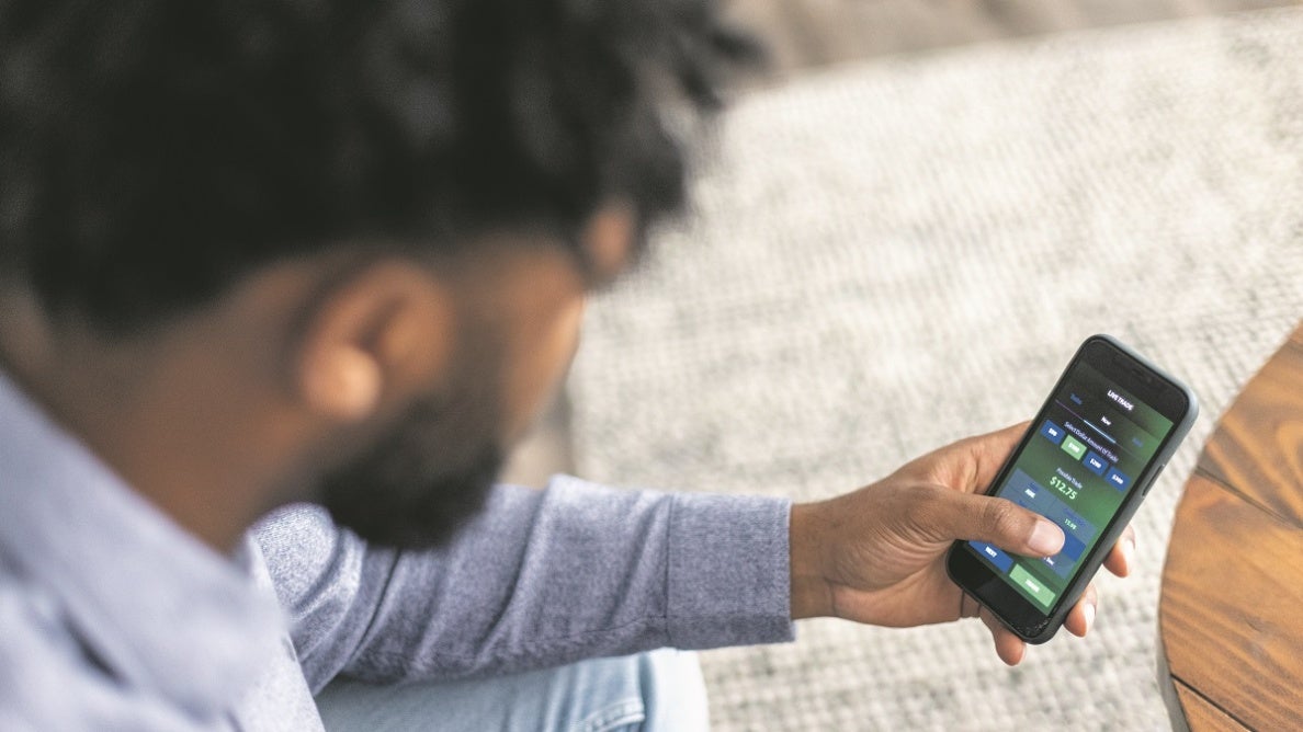 Black trader looking at stocks on his phone