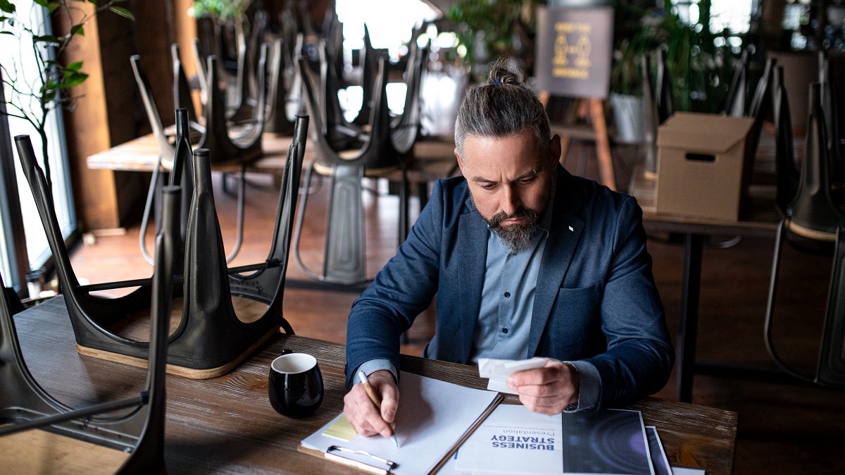 Small business owner calculating figures, looking at camera.