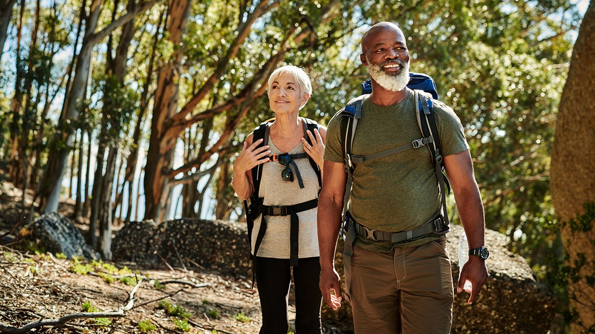 An older woman and man walking through a wooded area