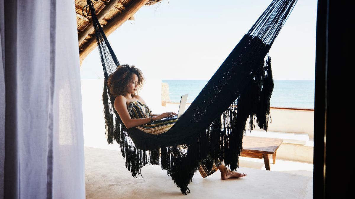 Employee works from hammock in sunny beachside location