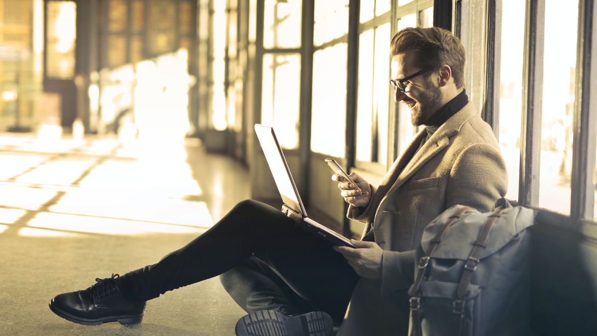 Remote worker smiles at phone while sitting in an airport