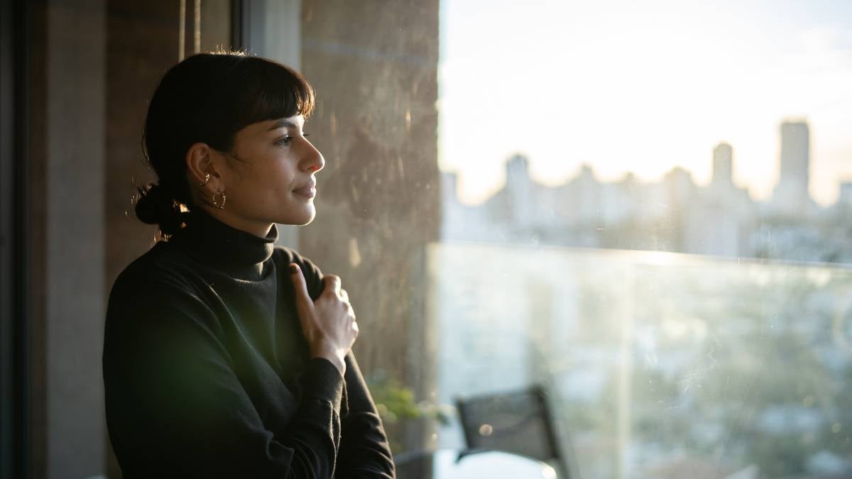 A woman looks out a window after quiet quitting her office job