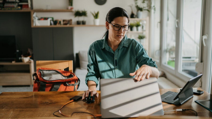 Woman closes her laptop while the sun beams through the window. Work is over for the day.