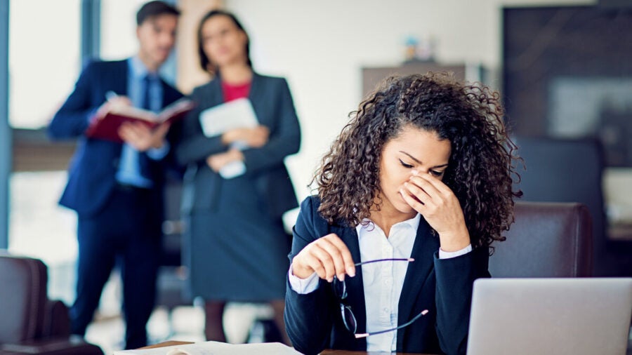 Businesswoman under pressure as managers look on and discuss her in the background