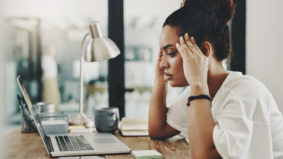 Shot of a young employee looking stressed while using a laptop in her home office