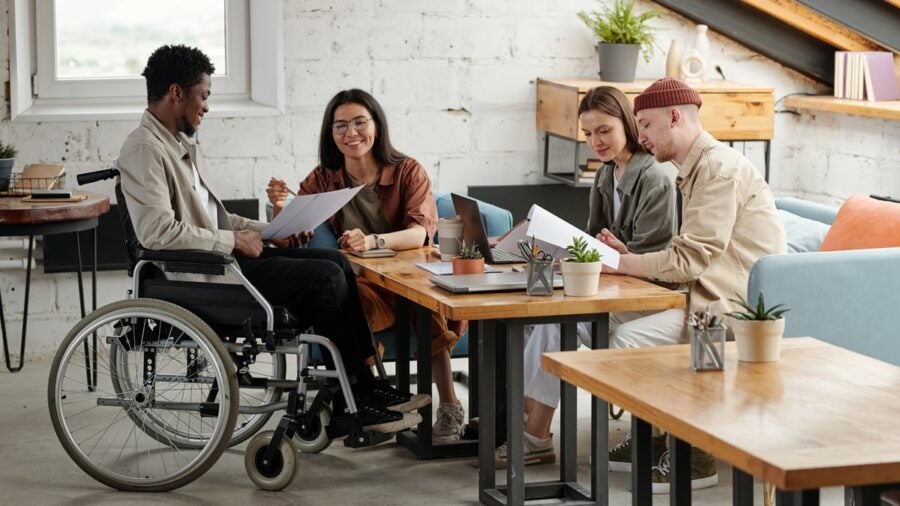 Two Pairs Of Intercultural Employees Working In Small Groups By Workplace